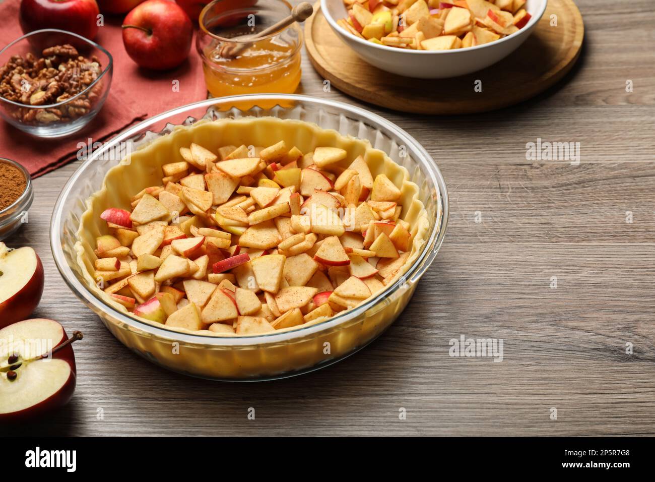 Raw dough and ingredients for apple pie on wooden table Stock Photo