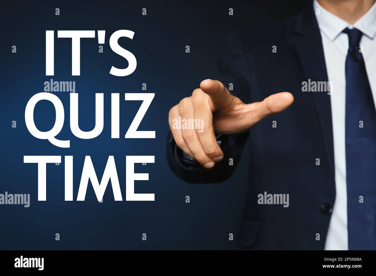Man pointing at phrase IT'S QUIZ TIME on dark blue background, closeup ...