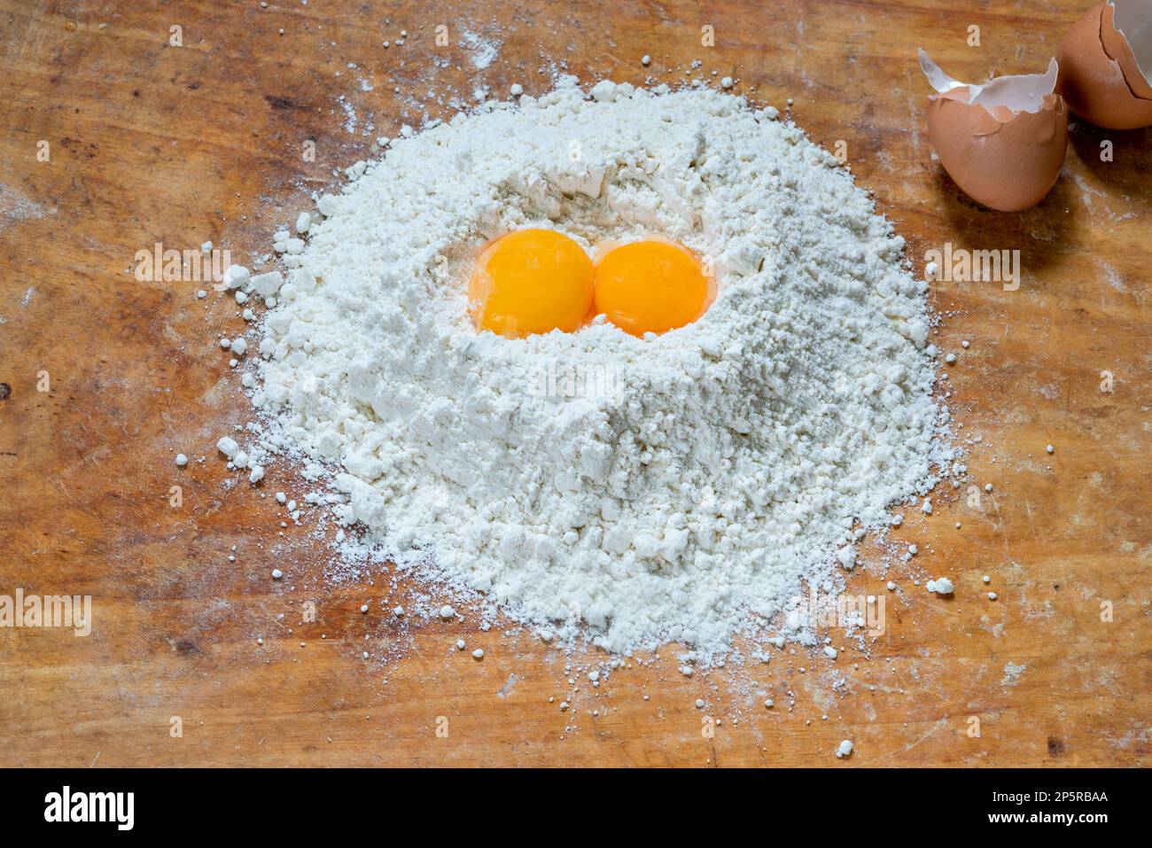 Flour and two egg yolks on wooden board Stock Photo