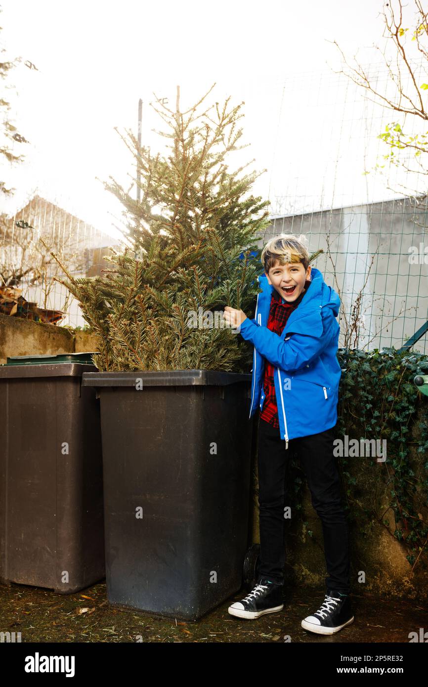 End of holidays. Boy throw Christmas tree in the Garbage bin Stock Photo Alamy