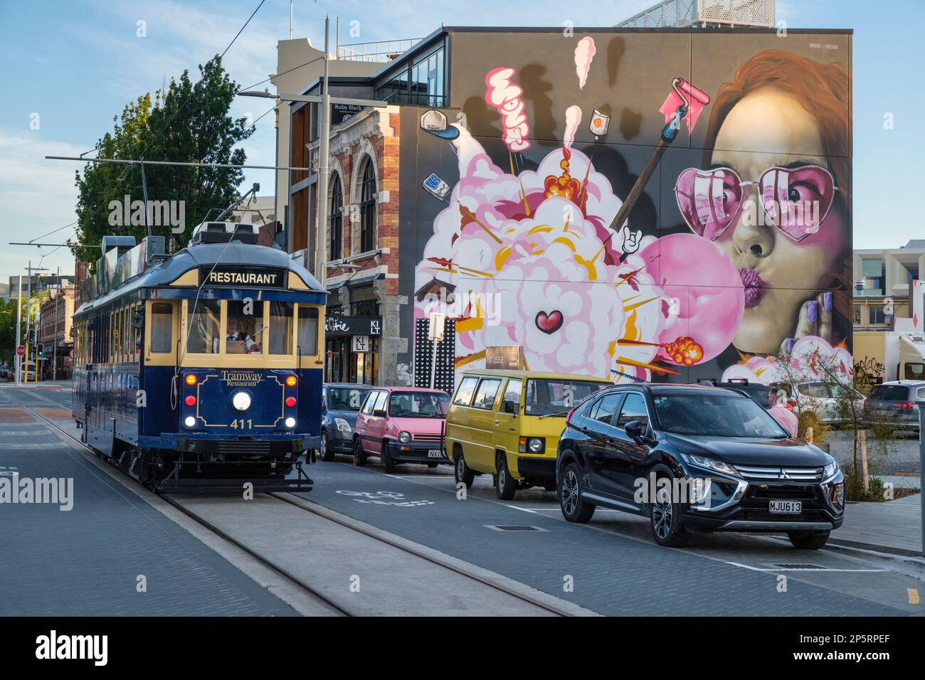 A restaurant tram in High Street, Christchurch,  passes one of the many murals in the city. South Island, New Zealand. Stock Photo