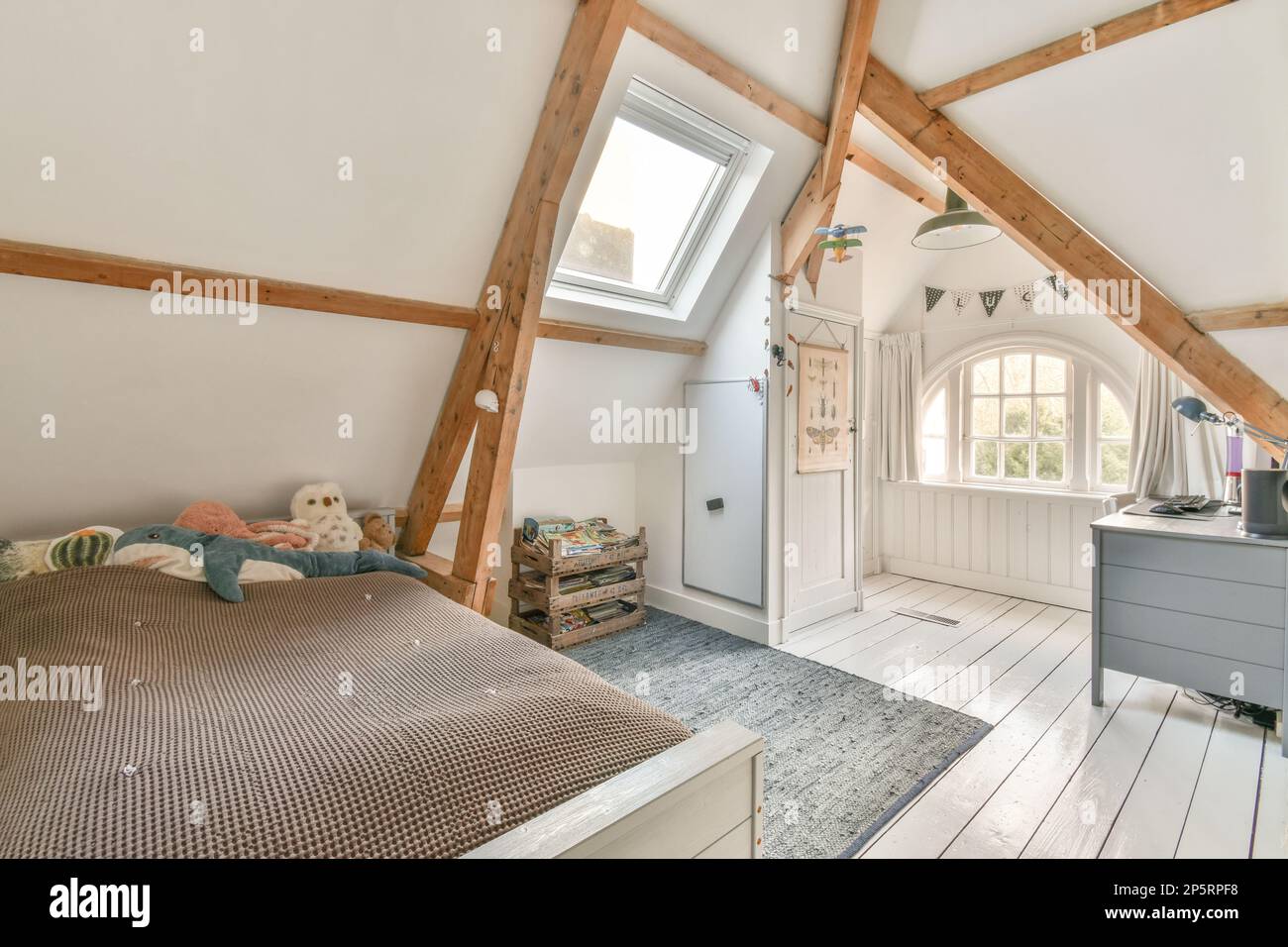 an attic bedroom with wood beams and white walls, hardwood flooring and