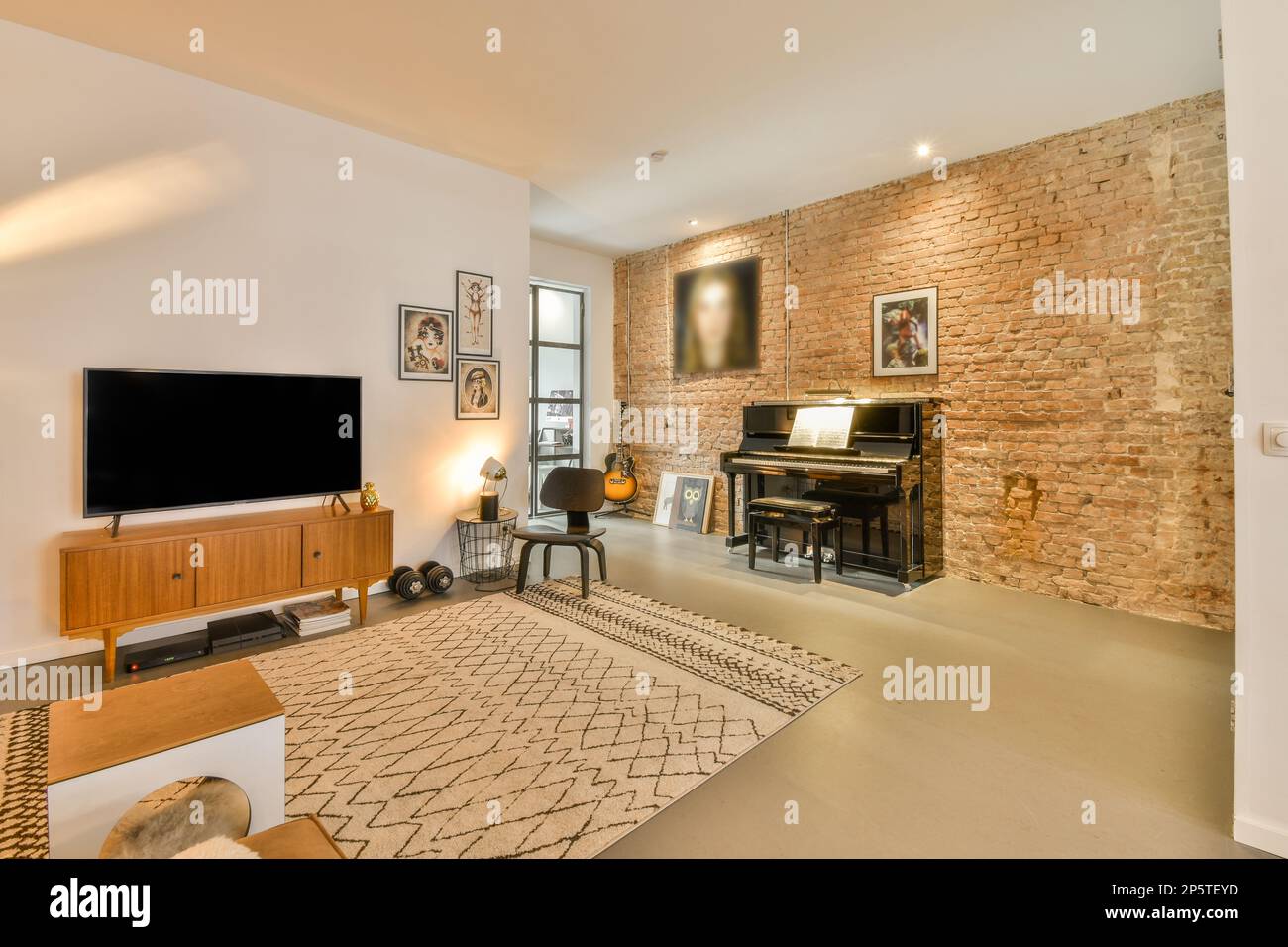 a living room with an old brick wall in the background and a piano on the floor next to the fireplace Stock Photo