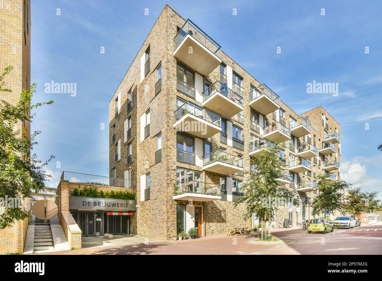 an apartment building on a street with cars parked in front and people ...