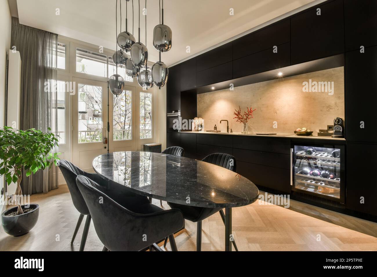 a modern kitchen and dining area in a house with wood flooring, black ...