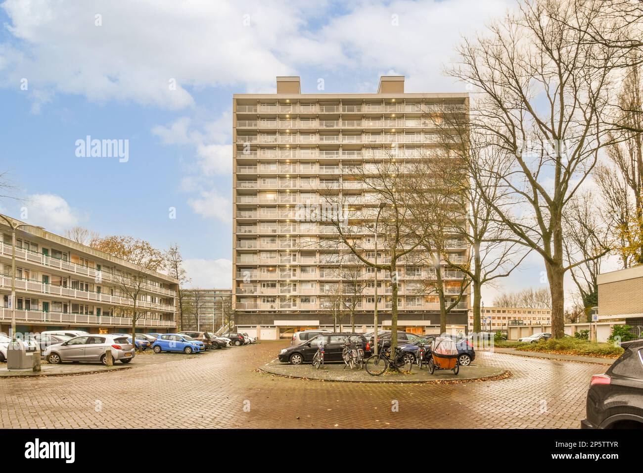 a parking area in front of an apartment building with cars parked on ...