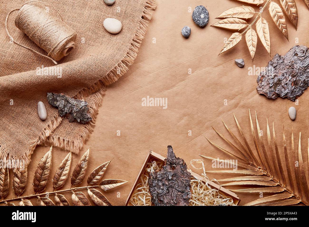 Natural brown eco-friendly, sustainable background with copy space. Natural Cotton Thread, tree bark, golden leaves, pebbles on crafting paper. Stock Photo