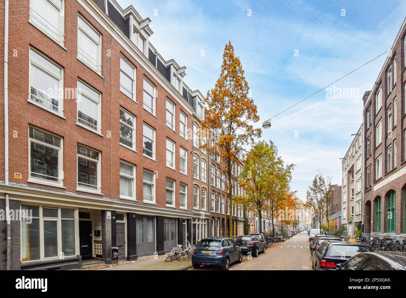 a city street with cars parked on the side and buildings in the back ...