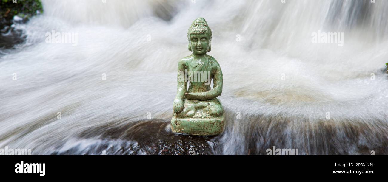 Buddha sculpture sitting in flowing water cascade Stock Photo