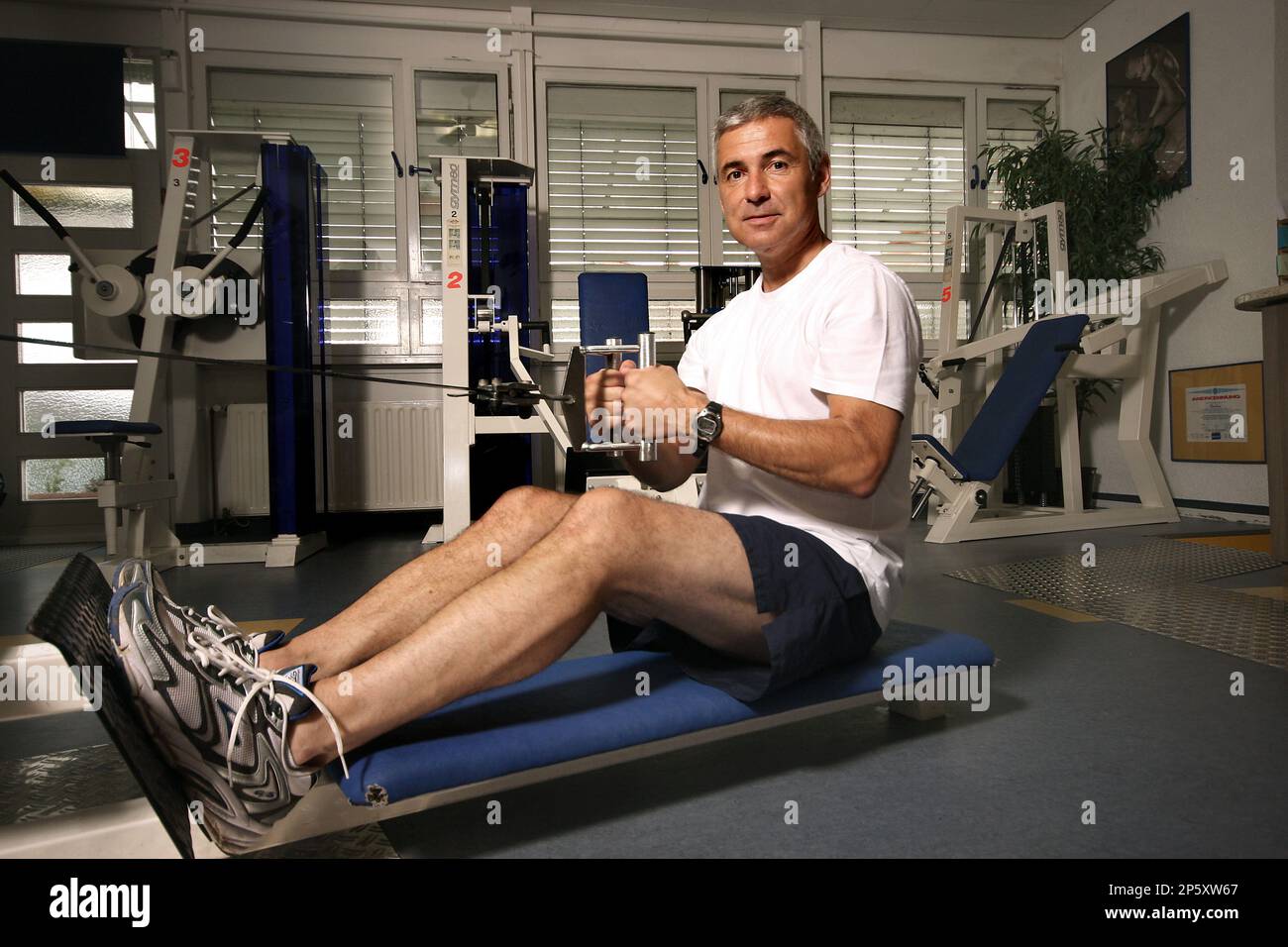 elderly man at a rowing machine in the gym Stock Photo