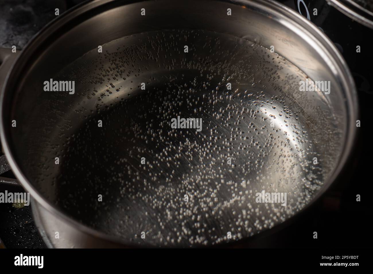 The water in the pot starts to boil. A saucepan on a gas stove with air bubbles from boiling