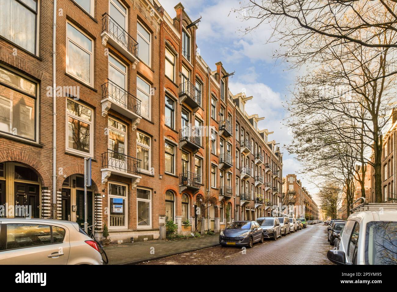 a city street with cars parked on the side and buildings in the back ...