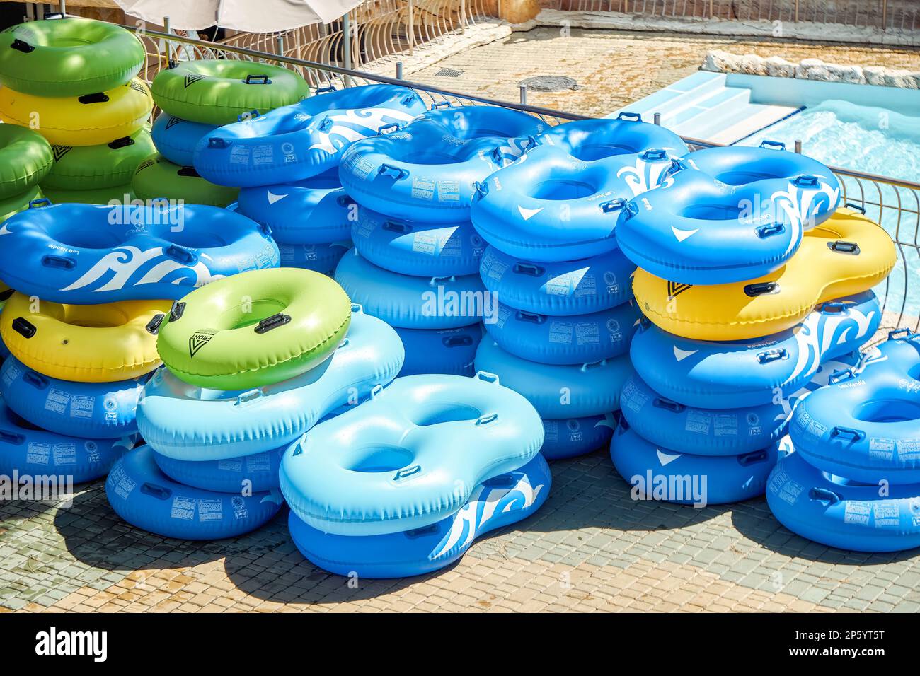 Multi-colored rubber rings for swimming pool put in rows at bright sunlight. Stacks of inflatable swim-rings ready for tourists in water park Stock Photo