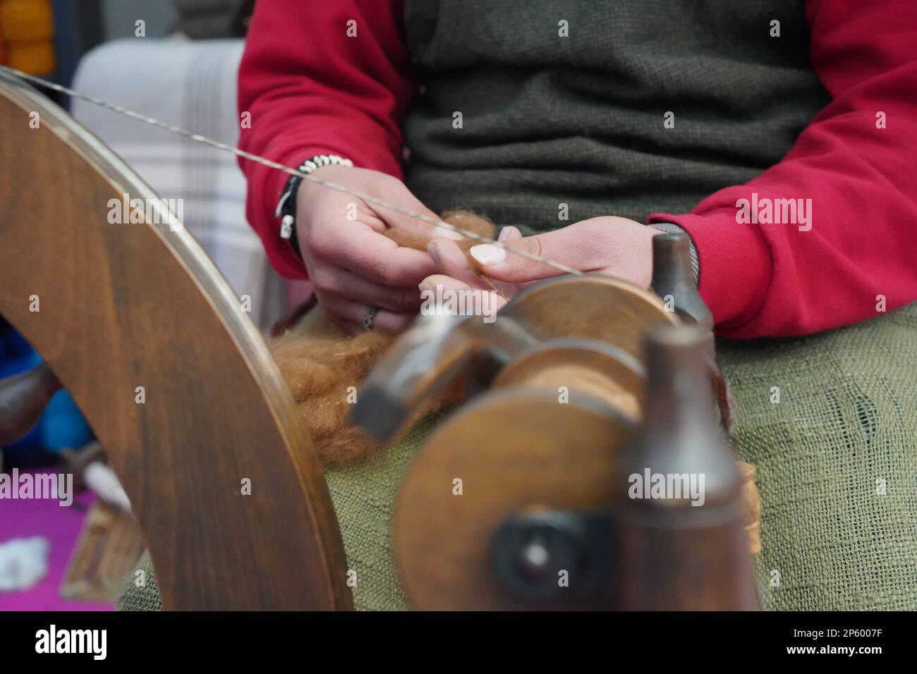 A street artist sewing manufacturing with traditional spinning wheel. Handcraft fiber sew by