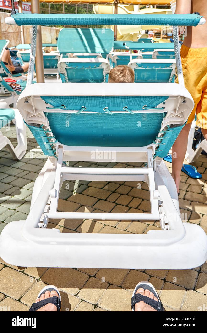 Backs of deck chairs for tourists to relax after activities in water park. Blue sun loungers in recreational area at summer resort closeup Stock Photo