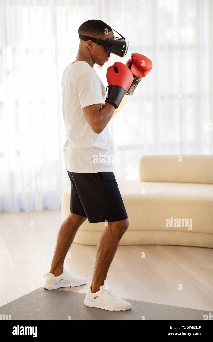 African american guy sportsman in VR glasses boxing at home Stock Photo