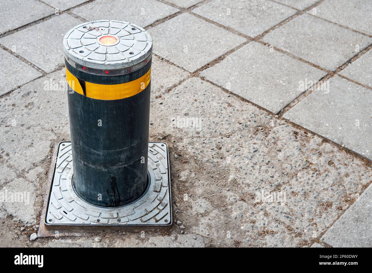 Black automatic lifting pole with yellow strip on pavement in city closeup. Equipment for vehicle traffic regulation on modern town road Stock Photo