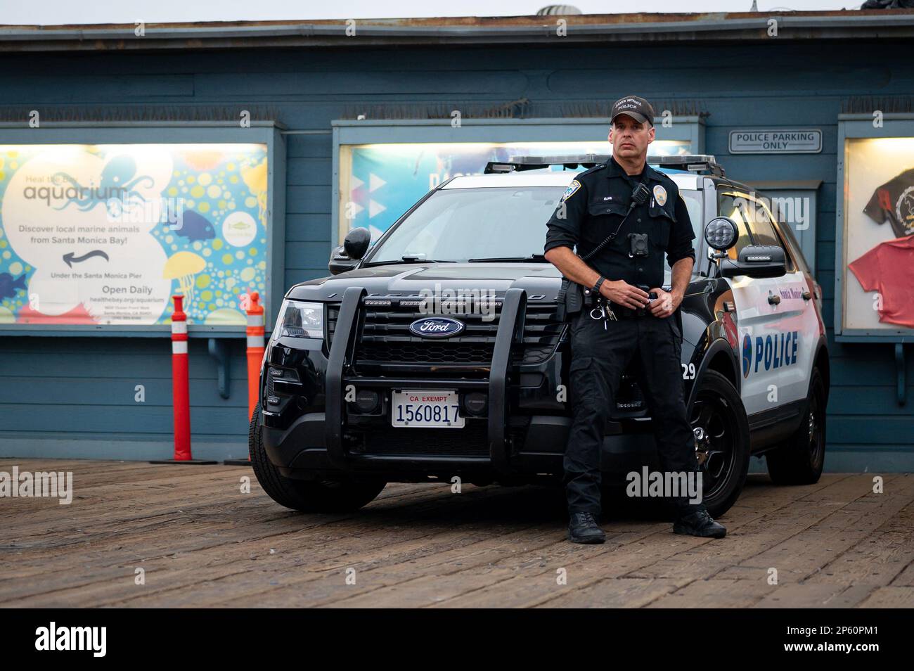 A serious policeman next to his Ford Police Interceptor SUV keeping watch on the Santa Monica pier Stock Photo