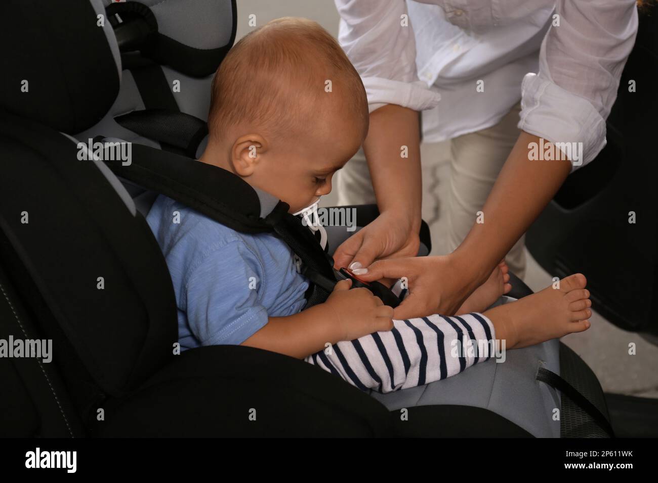 Mother fastening her son in child safety seat inside car Stock Photo ...