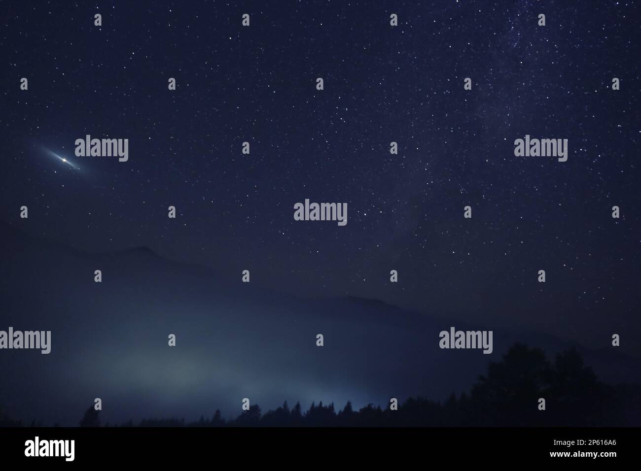 Picturesque view of night sky with beautiful stars over foggy hill ...