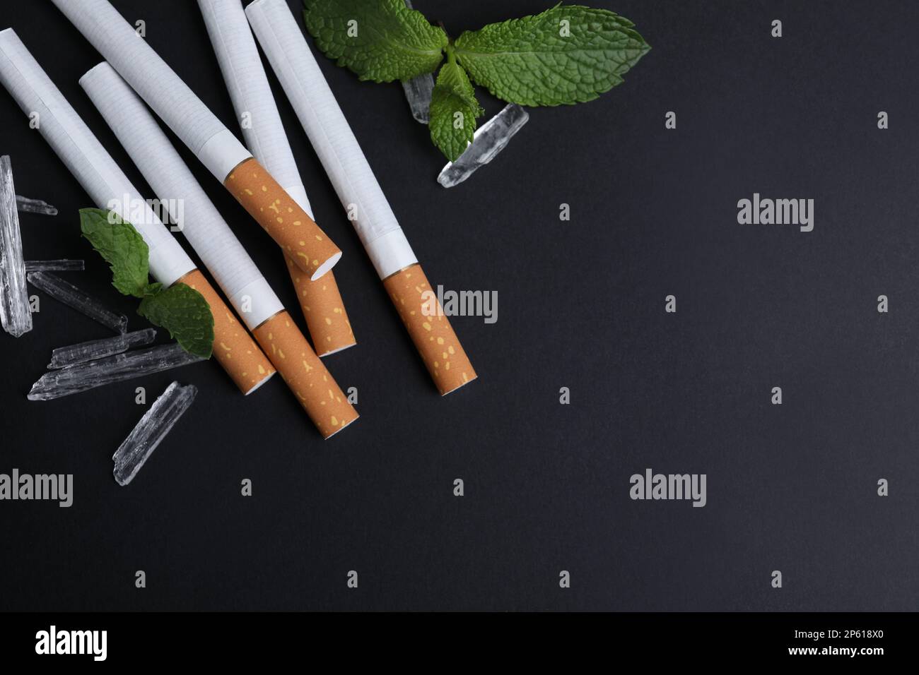 Cigarettes, menthol crystals and mint on black background, flat lay. Space  for text Stock Photo