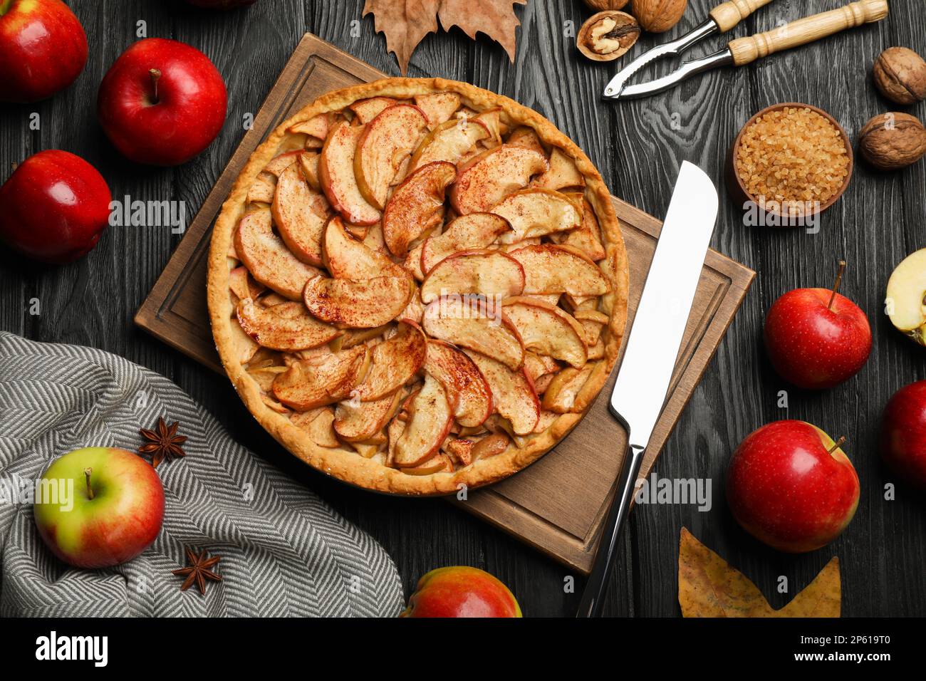 Delicious apple pie and ingredients on black wooden table, flat lay Stock Photo