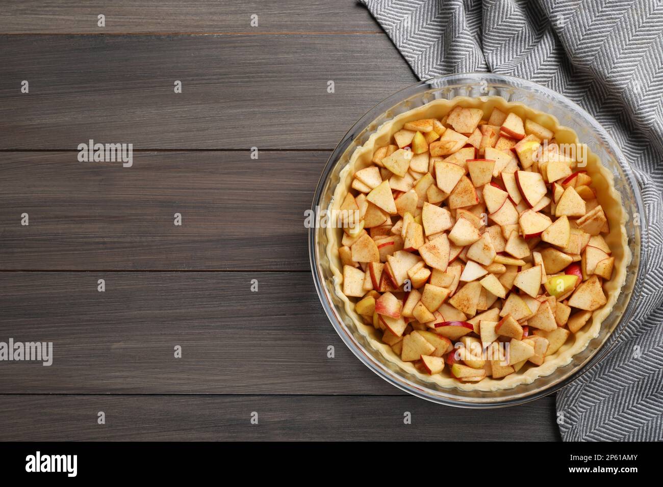 Top view of raw dough with apple slices on wooden table, space for text. Baking pie Stock Photo