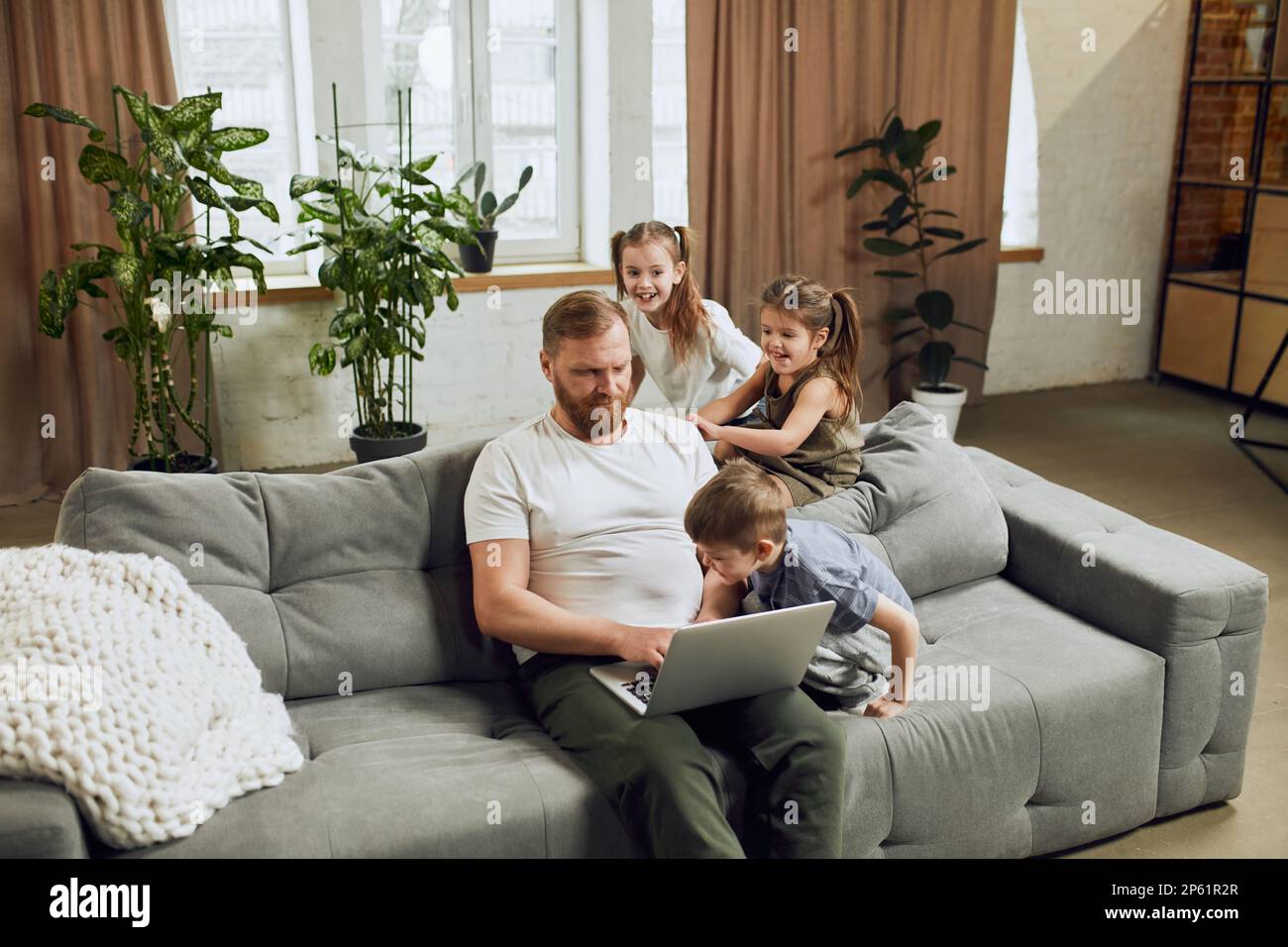 Mature man, father sitting on couch at home and working remotely on