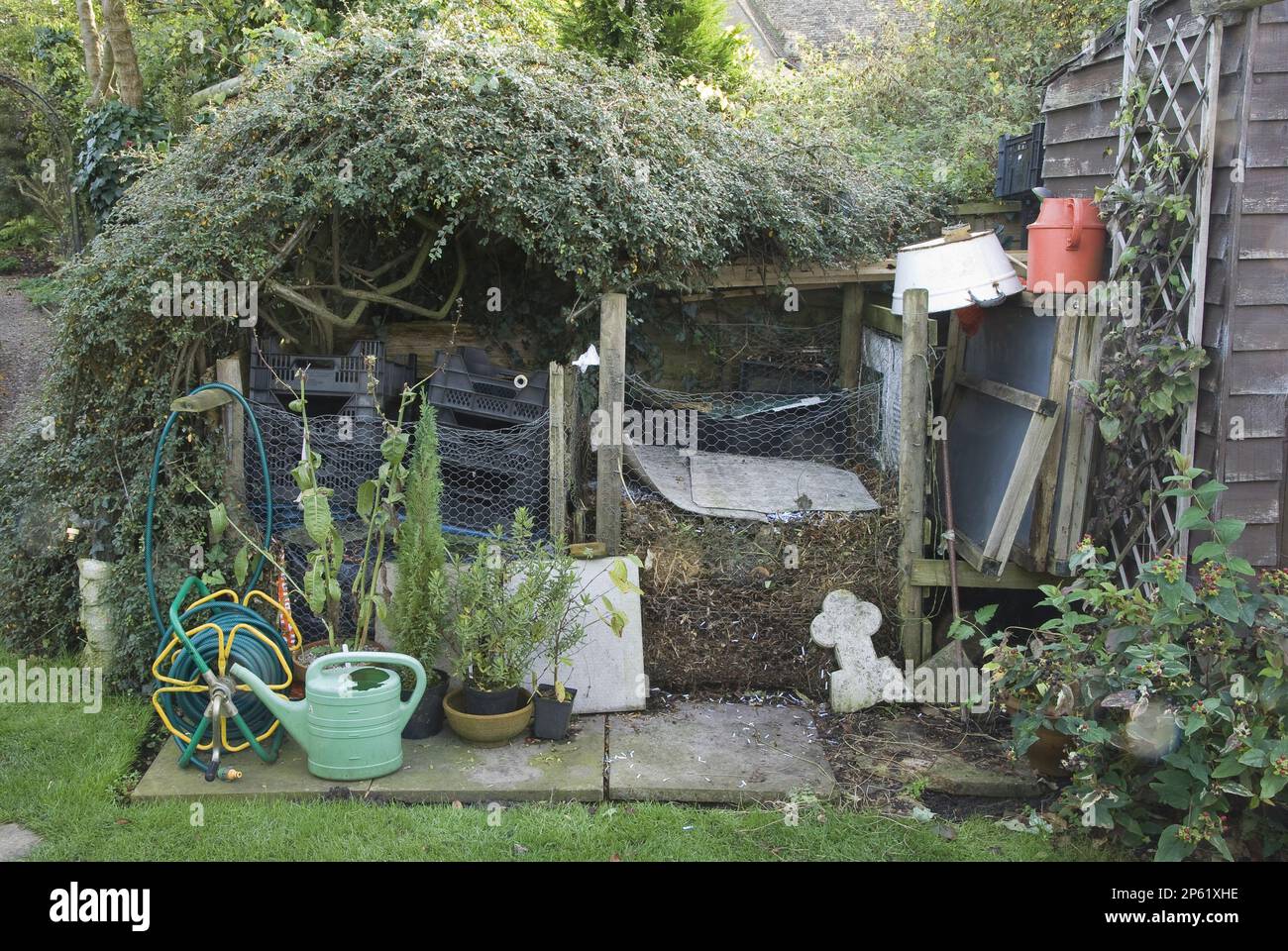 green clippings compost stack in wire mesh with garden equipment busy productive Stock Photo