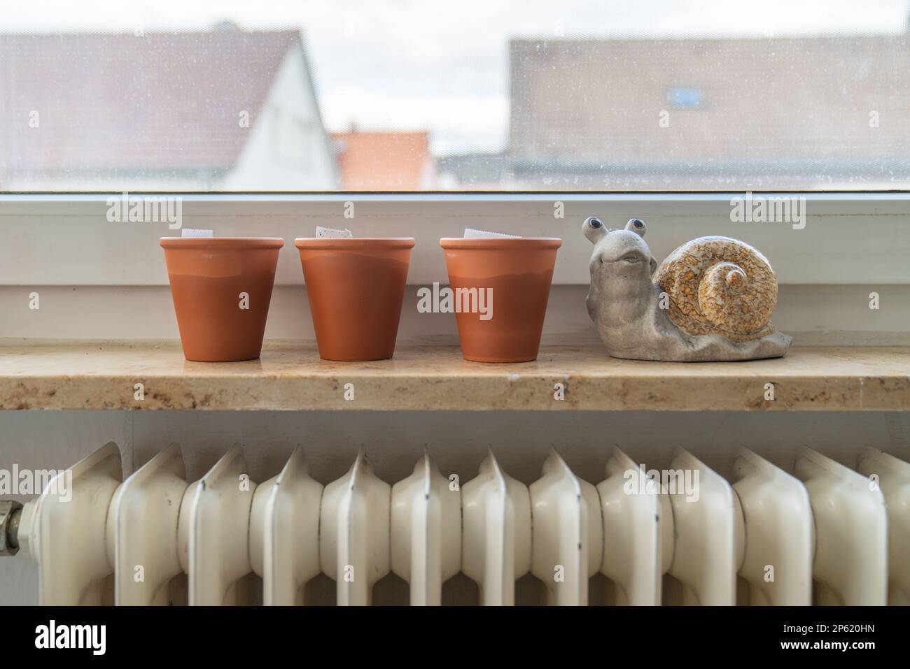 Three terracotta pots on the windowsill with the figure of a snail. Stock Photo