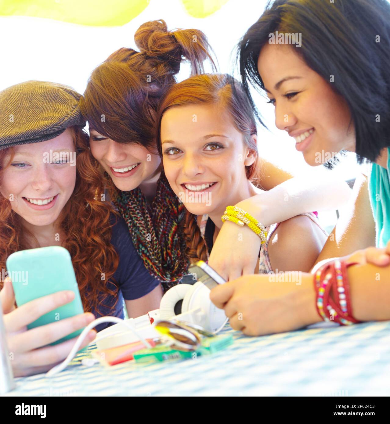 Teen technology. A group of adolescent girls laughing as they look at something on a smartphone screen. Stock Photo