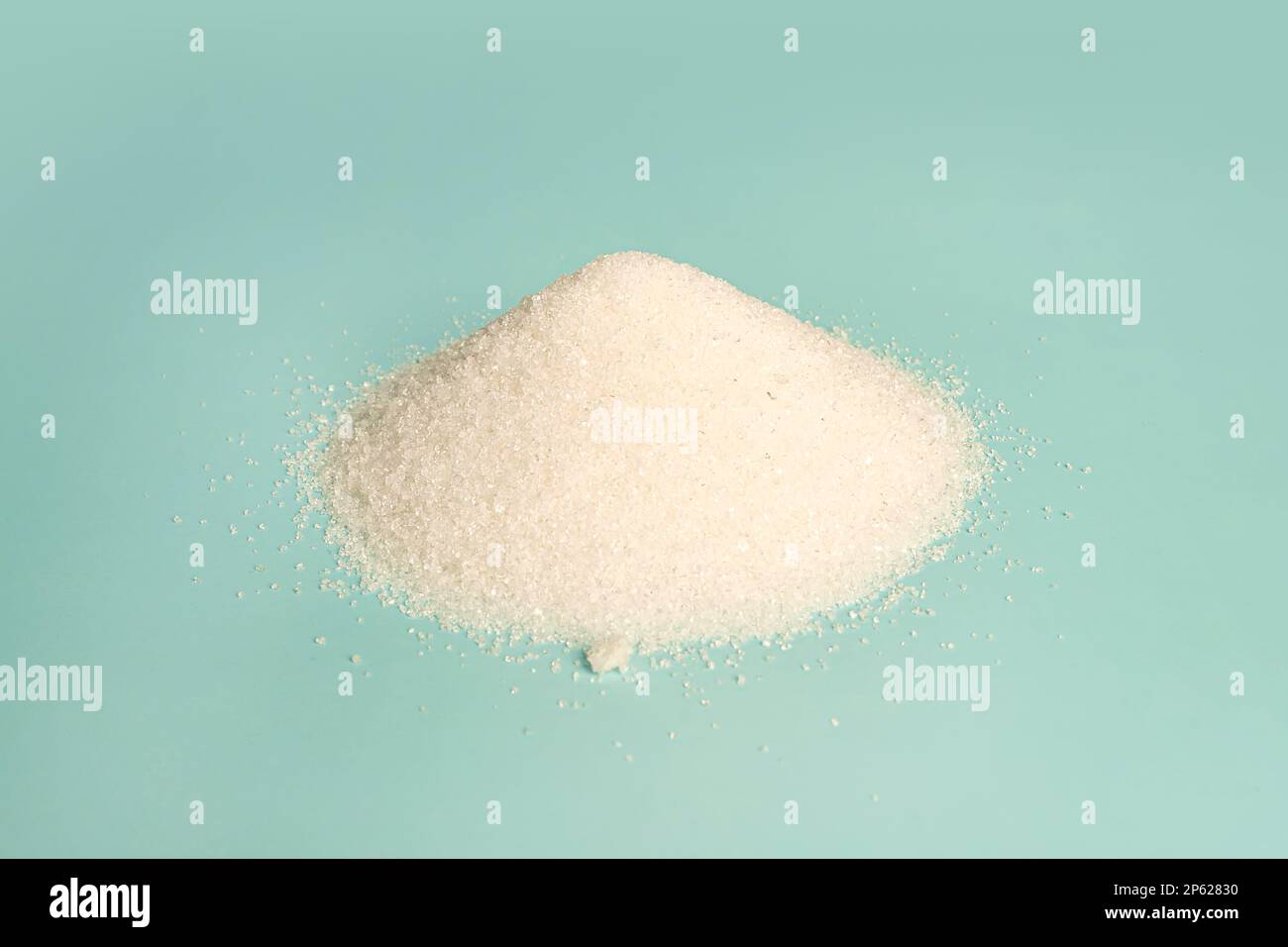 white granulated sugar on a blue background. Stock Photo