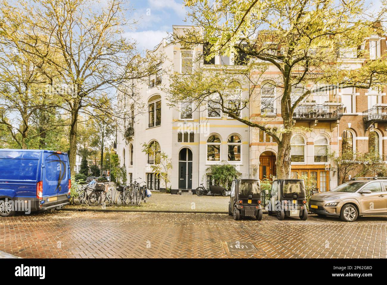 a city street with cars parked on the side and bicycles parked in front ...