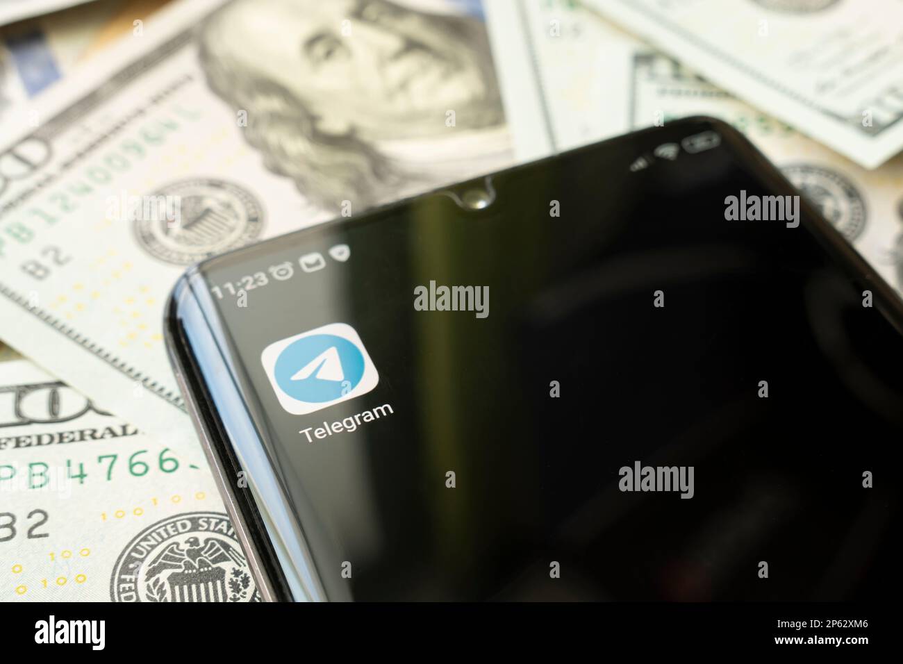 Smartphone screen with Telegram app and lot of hundred dollar bills. Business and social networking concept. the application icon on the black screen Stock Photo