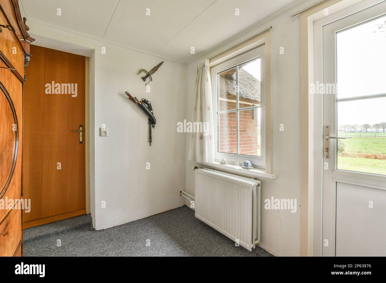 a door and window in a room with wood paneled walls, grey flooring and white trim on the doors Stock Photo