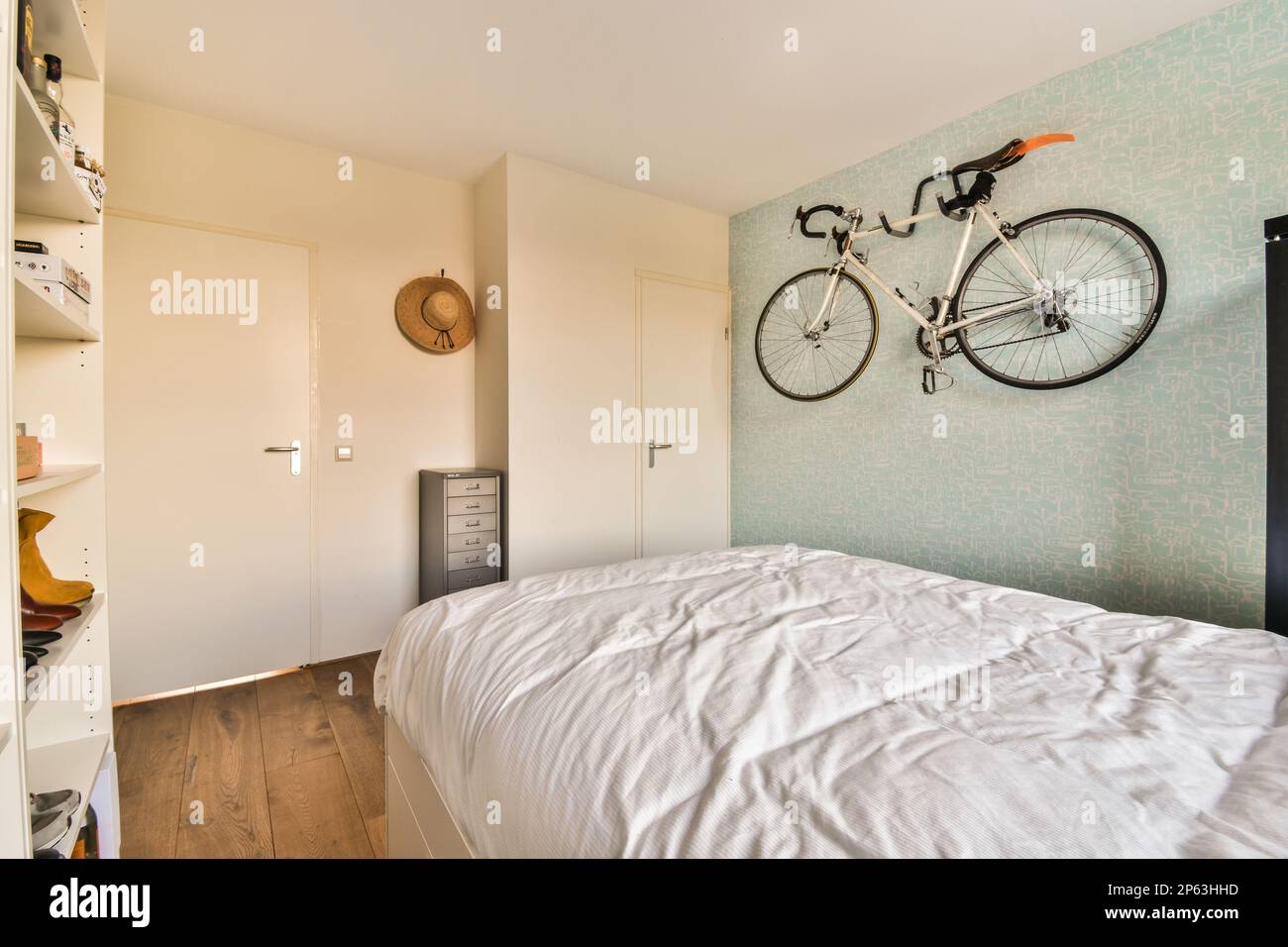 a bedroom with a bike mounted on the wall above it and a bed in the room is made out of wood Stock Photo Alamy