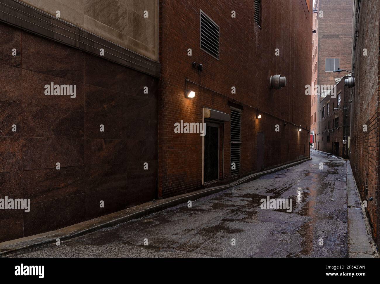 Puddles of water on uneven pavement in an alleyway between buildings in downtown Cleveland, Ohio Stock Photo