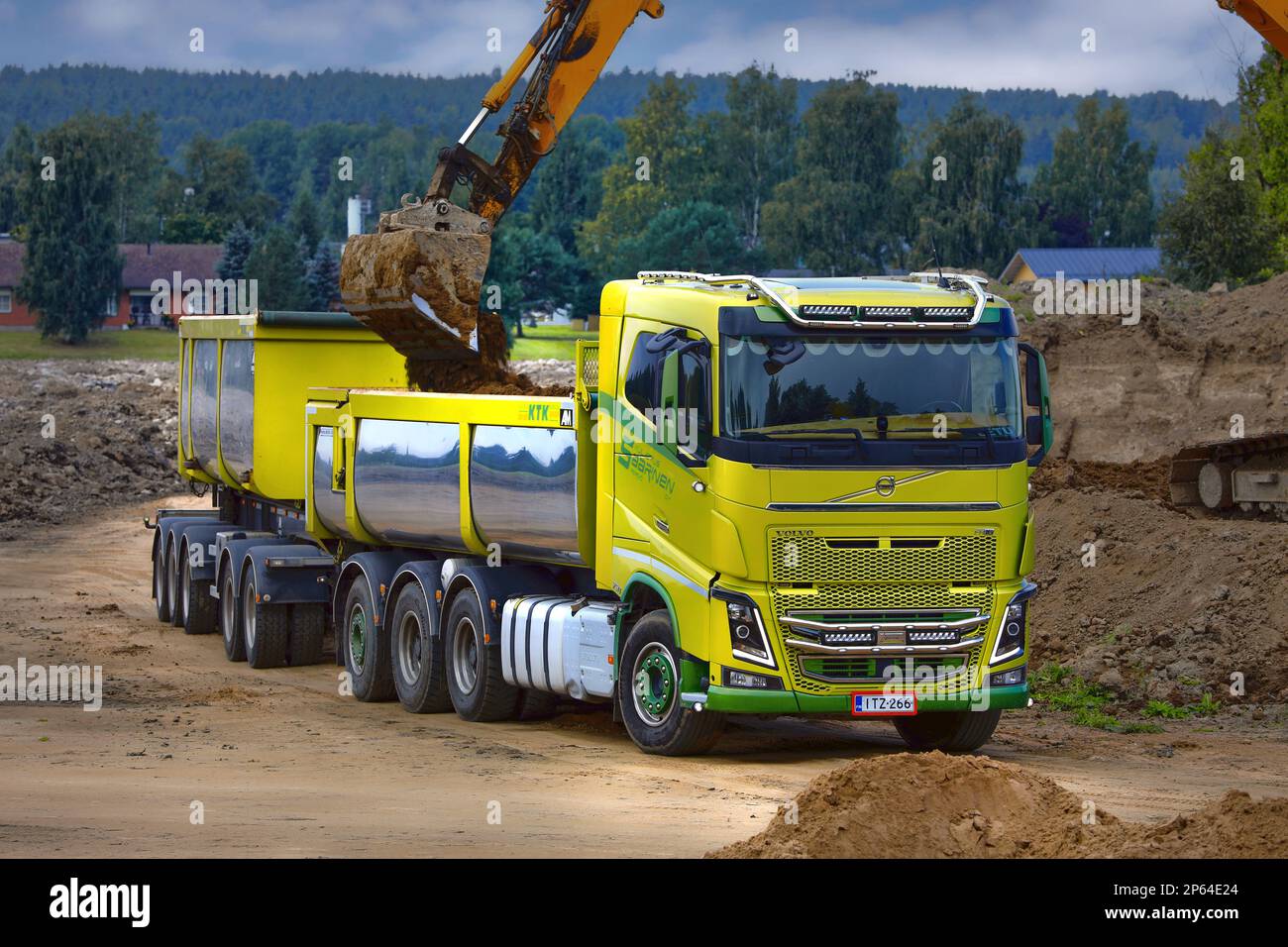 Tracked excavator loading soil onto green Volvo FH16 truck cassette trailer. Salo, Finland. August 27, 2022. Stock Photo