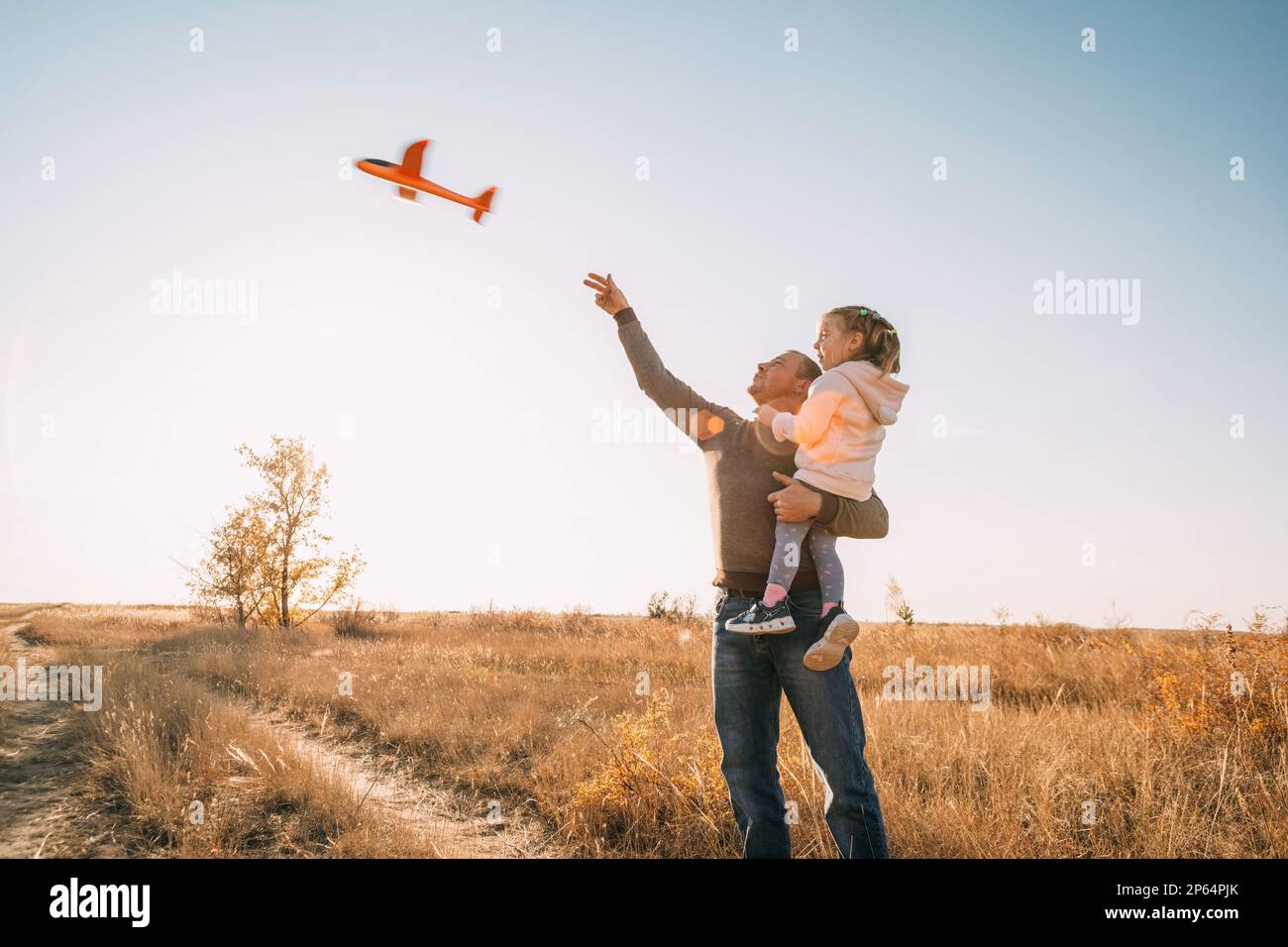 Happy Father And Child Having Fun Playing Outdoors. Smiling Young Dad And Daughter Spending Time Together, let an airplane into the sky Stock Photo