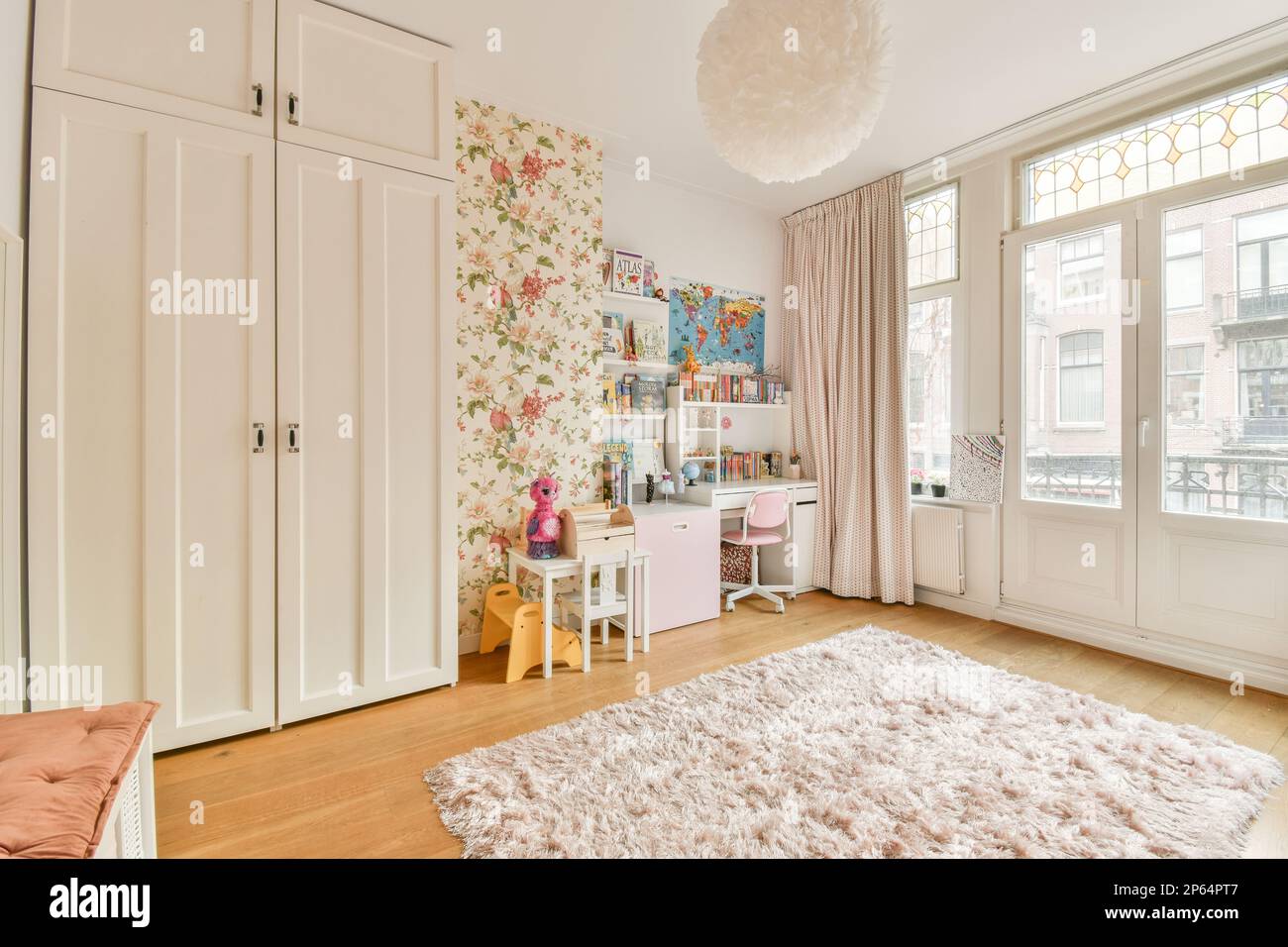 a girl's bedroom with floral wallpaper and white wardrobes in the room is decorated with pink