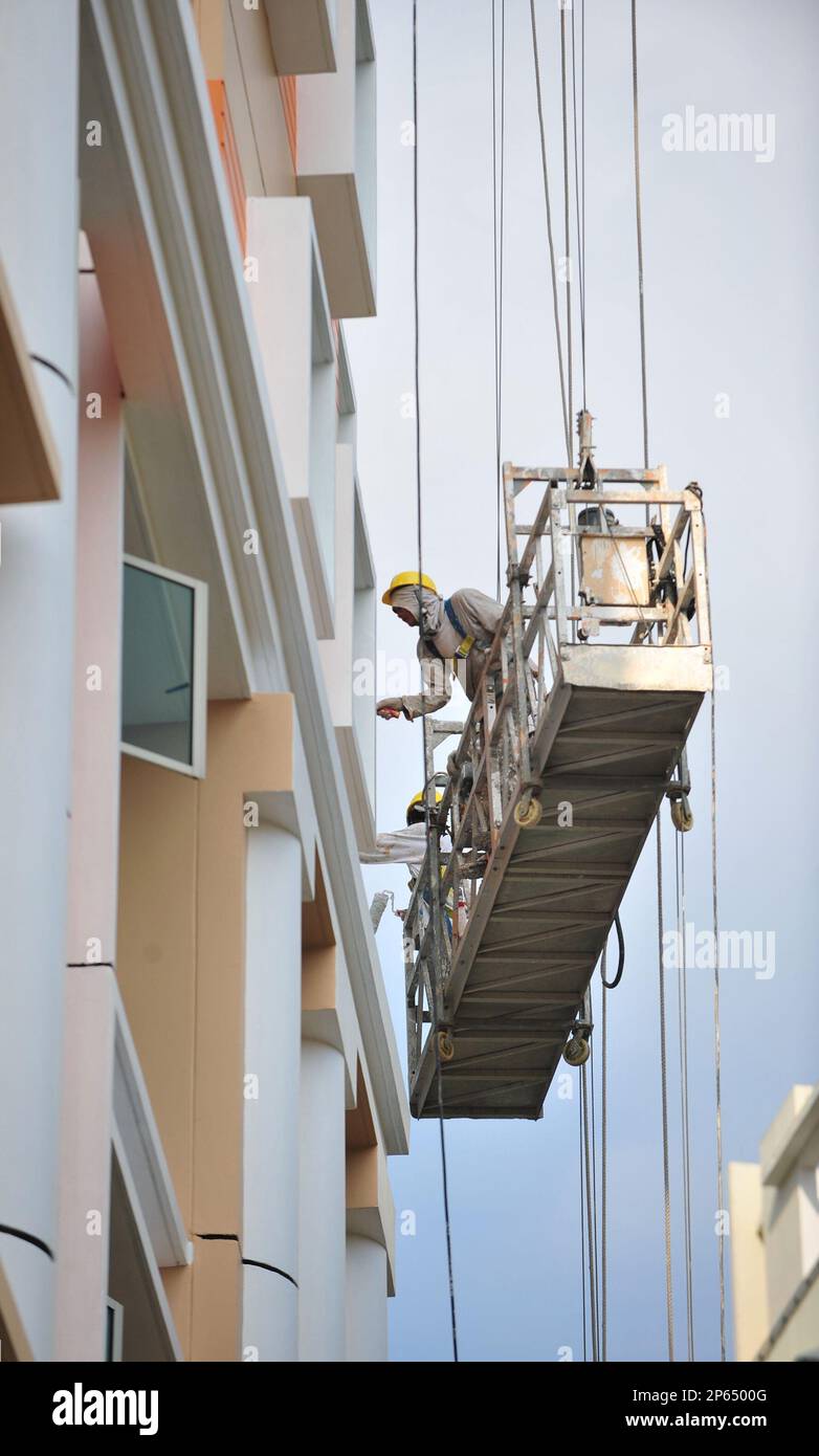 Workers on a gondola paint the exterior of a HDB flat in Singapore