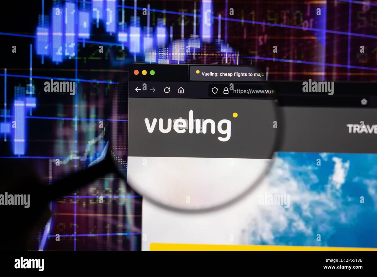 Vueling airline company logo on a website with blurry stock market developments in the background, seen on a screen through a magnifying glass Stock Photo