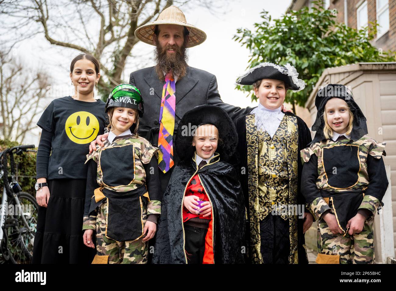 London, UK.  7 March 2023. A father and children in Stamford Hill, north London, dressed in colourful costumes celebrate the Jewish festival of Purim. The festival involves the reading of the Book of Esther, describing the defeat of Haman, the Persian king's adviser, who plotted to massacre the Jewish people 2,500 years ago, but the event was prevented by Esther’s courage.  Credit: Stephen Chung / Alamy Live News Stock Photo