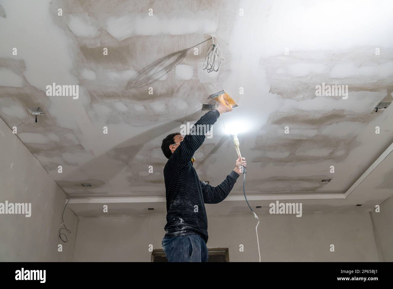 hand sanding of the plasterboard ceiling with a trowel Stock Photo