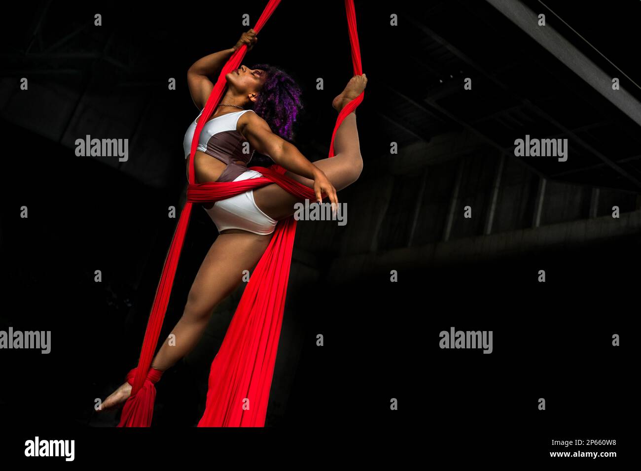 Mariale Contreras, a Venezuelan aerial dancer, performs on aerial silks during an art performance in an industrial space in Barranquilla, Colombia. Stock Photo