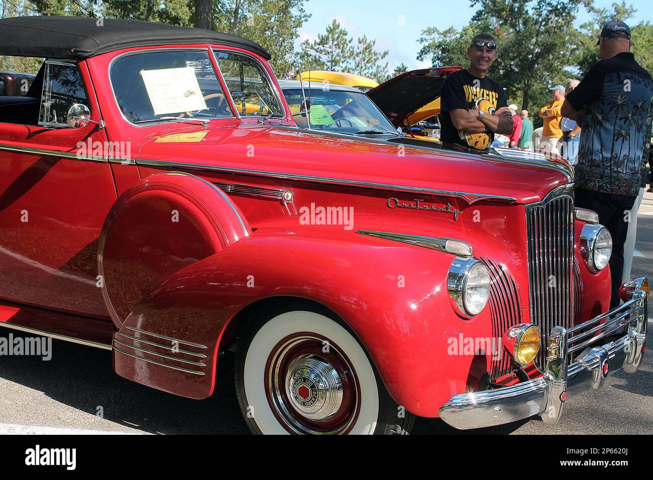 Spectators talk next to a red 1941 Packard owned by Jack and Annie