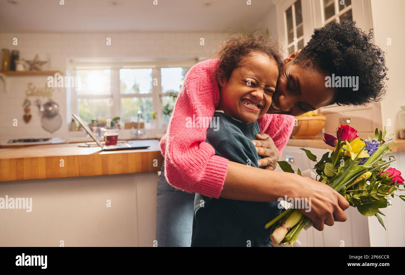 Mother holding bouquet and kissing son on Mothering Sunday Stock Photo