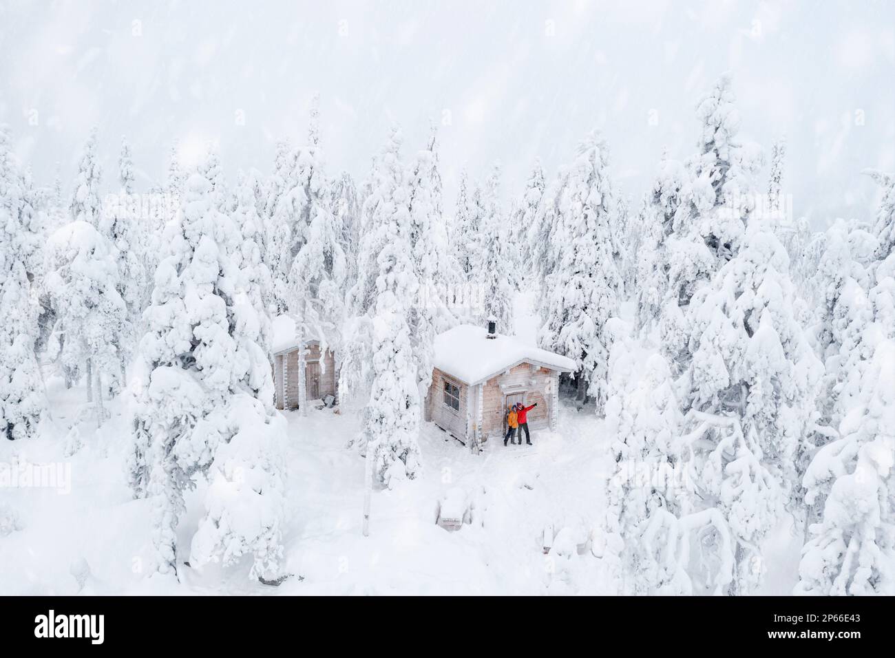 Aerial view of happy couple enjoying the winter holidays in a frozen hut in the snowy forest, Iso Syote, Northern Ostrobothnia, Lapland, Finland Stock Photo