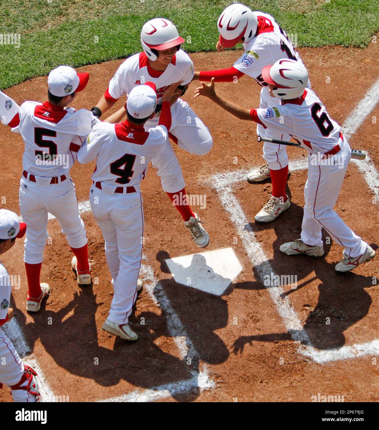 Tokyo's Satoru Aoyama leaps on home plate and celebrates with teammates after hitting a solo home run off Aguadulce, Panama, pitcher James Gonzalez in the first inning of the international championship baseball game at the Little League World Series, Saturday, Aug. 25, 2012, in South Williamsport, Pa. Tokyo won 10-2. (AP Photo/Gene J. Puskar) Stock Photo