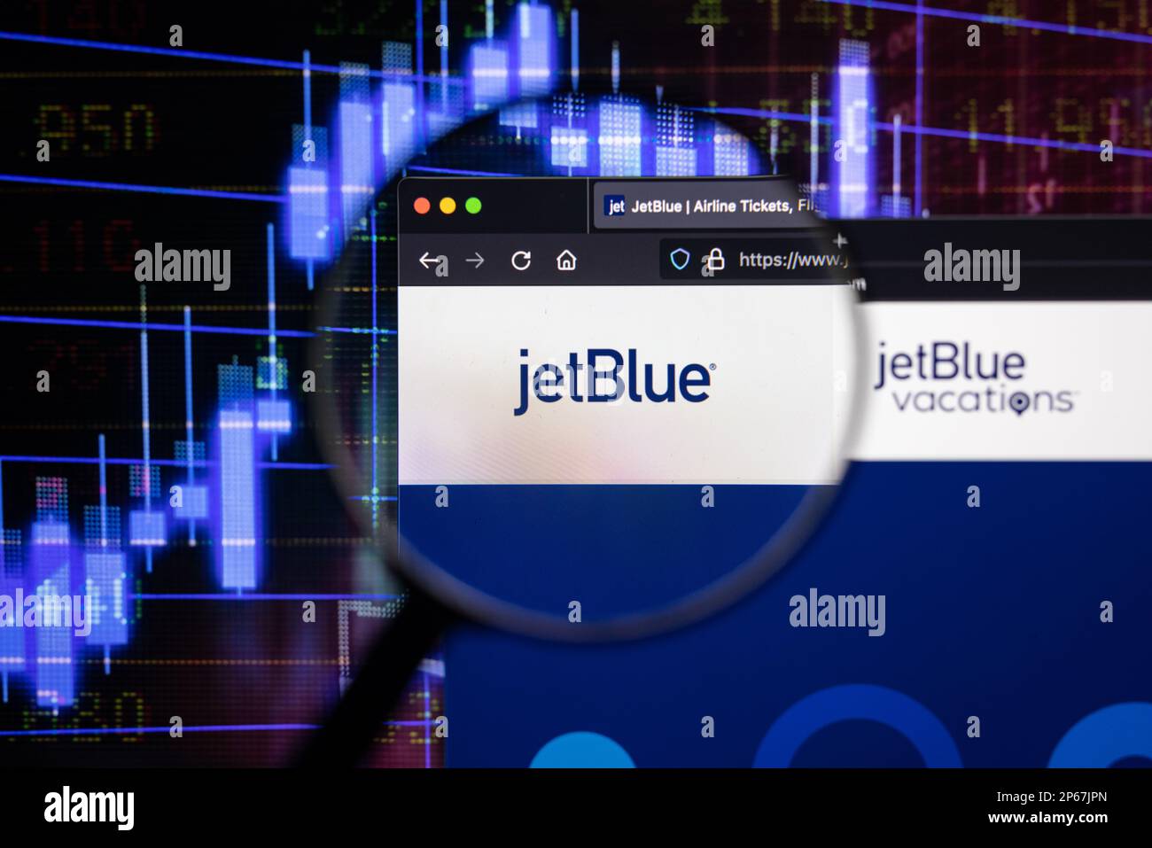 Jetblue company logo on a website with blurry stock market developments in the background, seen on a computer screen through a magnifying glass Stock Photo